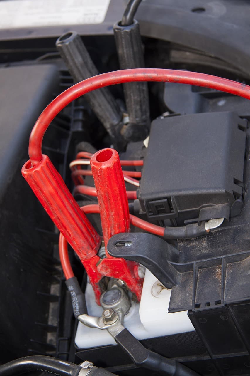 Red jump leads clamped to a car battery