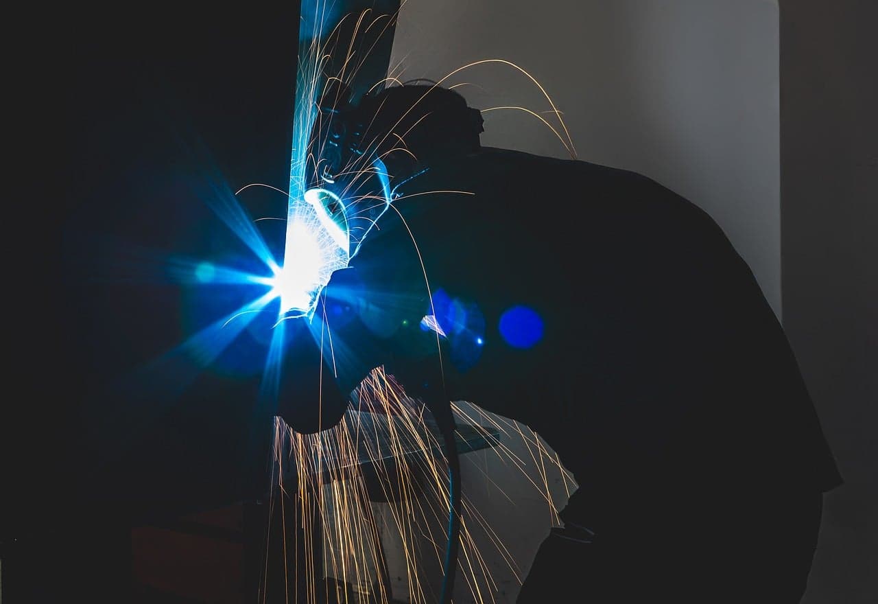 A welder at work, sparks flying in a dark workshop