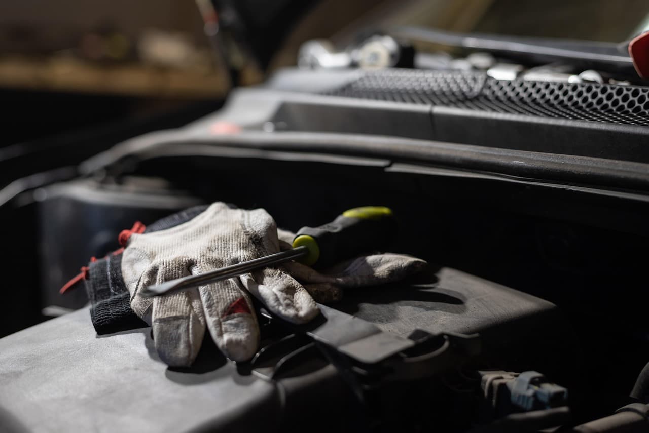 Work gloves and a screwdriver resting on an open engine bay
