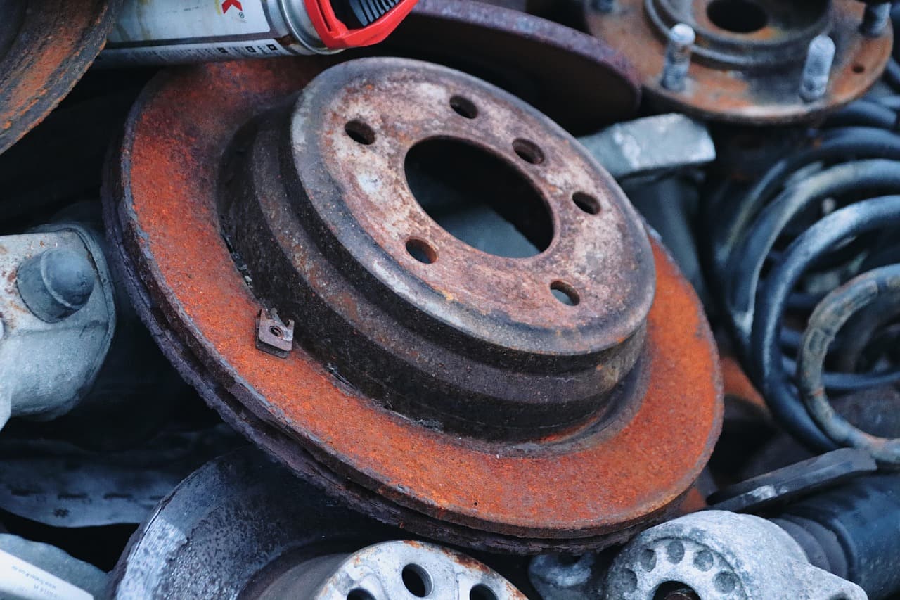 A rusted brake disc on a pile of scrap